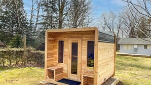 A small wooden cabin with a single entrance, a small porch, and a window. - Lakeside Layover, King Bed, Sauna! (Bayfield)