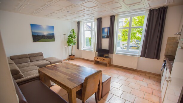 Una sala de estar con una mesa de madera, sofá y planta en maceta.