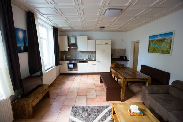 A modern kitchen with white cabinets, a wooden dining table, and a bench.
