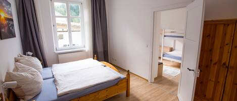A bedroom with a single bed, a wooden wardrobe, and a window with curtains.