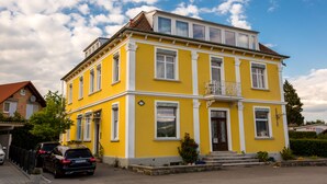 Un edificio amarillo con balcón, garaje y un coche estacionado.