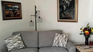 A grey sofa with patterned cushions, a black floor lamp, and two framed artworks on the wall. - Willow Cottage in the trees in West Sedona (Sedona)