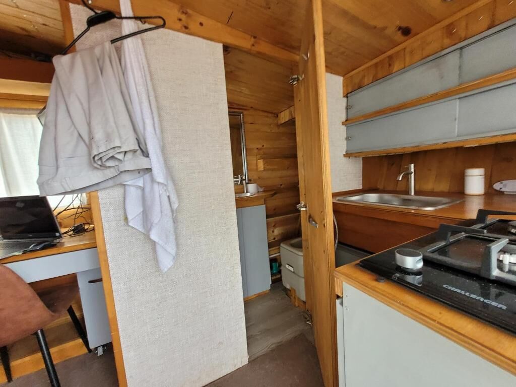 Een kleine keuken met houten kastjes, een spoelbak en een fornuis.