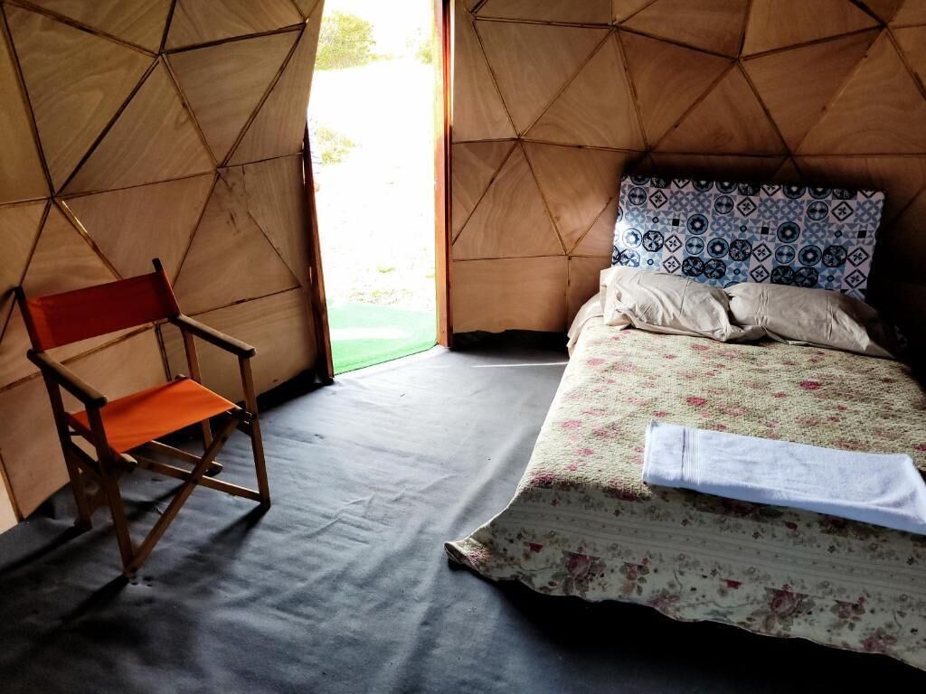 Une pièce aménagée comme une tente, avec un lit, une chaise et une vue sur l’extérieur.