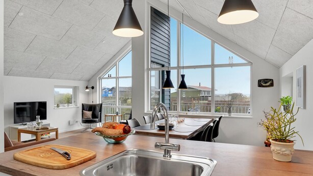 Eine moderne Küche mit einem großen Fenster, einer Spüle und einem Essbereich.