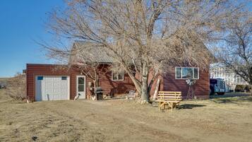 A house with a garage, a tree, a bench, and a truck.