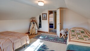 A bedroom with a bed, a wardrobe, a hanging coat rack, and a door leading to another room. - Charming 'Corral Creek Ranch House' in Circle (Circle)