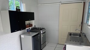 A compact kitchen with a gas stove, a refrigerator, and a sink.