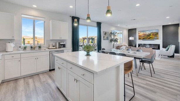 Una cocina moderna con armarios blancos, una isla central e iluminación colgante.