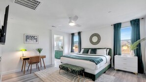 Un dormitorio moderno con cama, mesita de noche, escritorio, silla y un ventanal con cortinas.