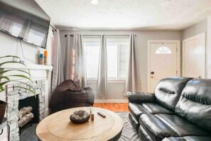 Cozy living space with a leather sofa, coffee table, and mounted TV.
