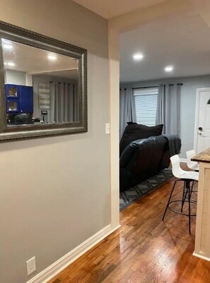 Cozy living space with a large mirror, kitchenette, and polished floors.