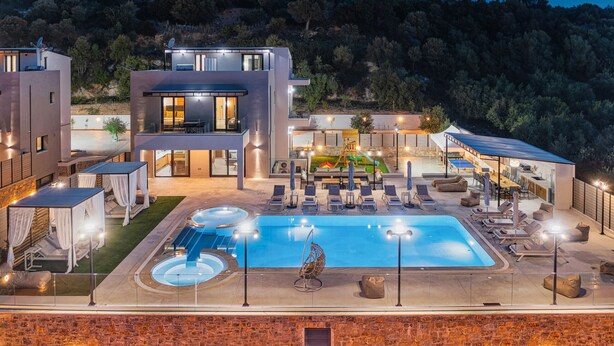 Een moderne villa met een zwembad, buitenzitplaatsen en uitzicht op de omliggende heuvels.
