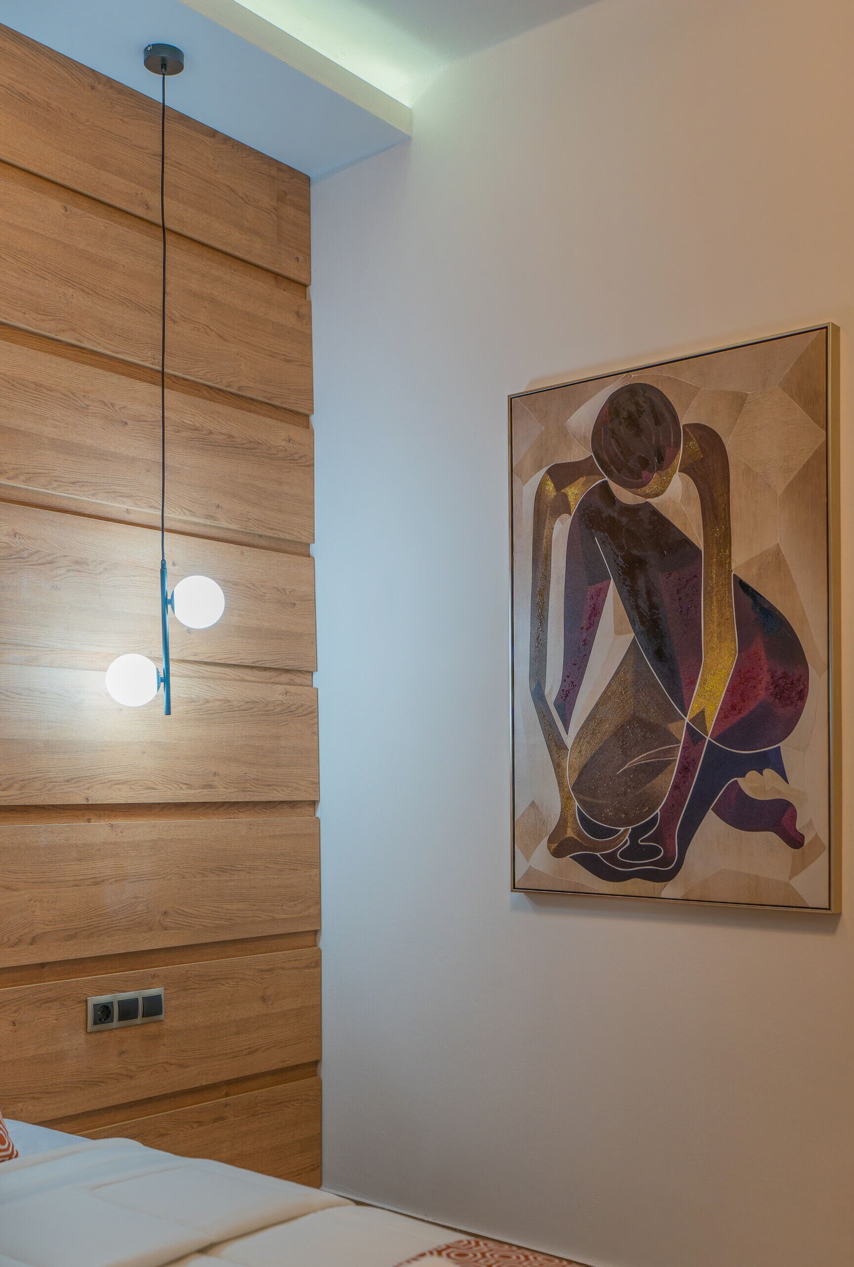 A room with wooden panel walls, a modern light fixture, and a geometric abstract painting.