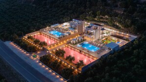A modern resort with multiple swimming pools, outdoor seating areas, and a well-lit landscape.
