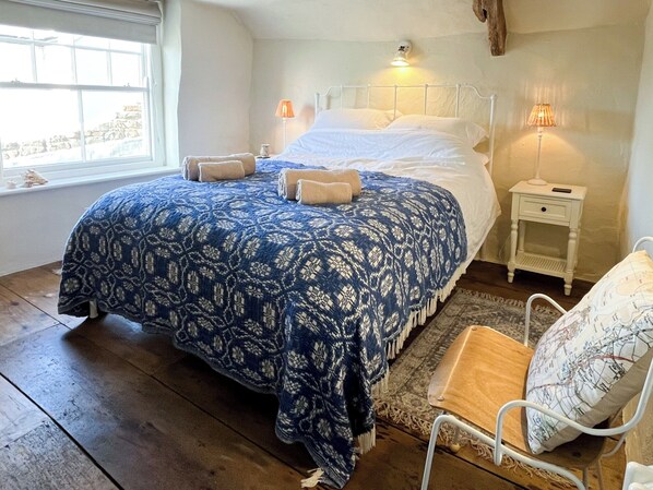 Ett sovrum med en stor säng, två sänglampor, ett fönster och en stol.