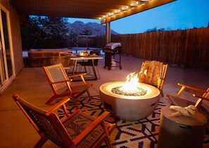 Un patio al aire libre con una chimenea, asientos y una parrilla.