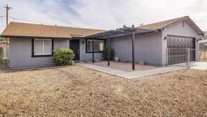 A modern two-story house with a covered patio, a garage, and a gravel driveway. - Live Centered W/ Hot Tub, Fire Pit In Joshua Tree 2 Bedroom Home by RedAwning (Joshua Tree)