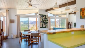 A modern kitchen with a dining area, large windows, and a view of the mountains. - Las Alas Del Sol- A Desert Architectural Gem 2 Bedroom Home by RedAwning (Joshua Tree)