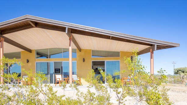 A modern building with a covered patio area, large windows, and a view of the surrounding landscape. - Las Alas Del Sol- A Desert Architectural Gem 2 Bedroom Home by RedAwning (Joshua Tree)