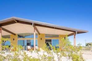 Un bâtiment moderne doté d’un patio couvert, de grandes fenêtres et offrant une vue sur le paysage environnant.