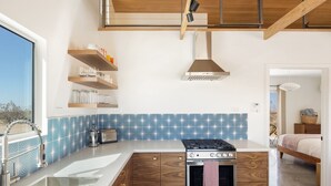 Une cuisine moderne dotée d’une cuisinière intégrée, de meubles en bois et d’un revêtement mural décoratif à motifs géométriques.