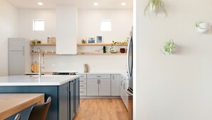A modern kitchen with a wooden dining table, grey cabinets, and a built-in oven. - Back Haus - Views, Dark Skies And Fire Pit! 1 Bedroom Home by RedAwning (Joshua Tree)