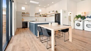 A modern kitchen with a central island, built-in appliances, and a dining area with a table and chairs. - Back Haus - Views, Dark Skies And Fire Pit! 1 Bedroom Home by RedAwning (Joshua Tree)