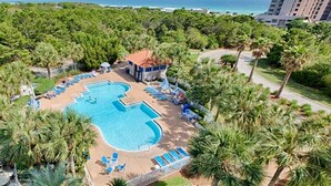 An aerial view of a resort with a large swimming pool surrounded by palm trees and lounge chairs. - Tops'l 1008a Chalet by RedAwning (Miramar Beach)