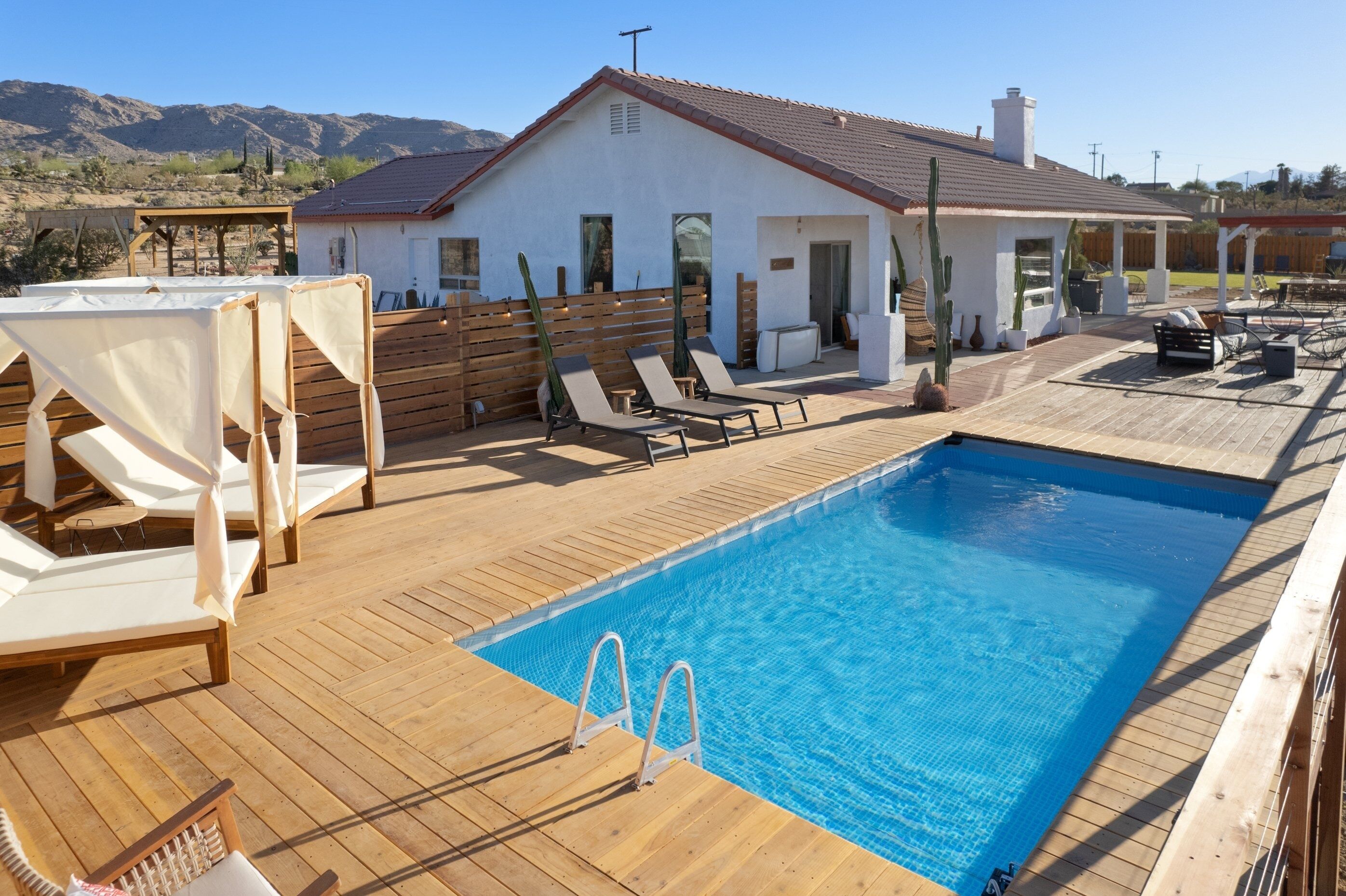 Area piscina con lettini e terrazza in legno.