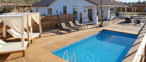 Area piscina con lettini e terrazza in legno.