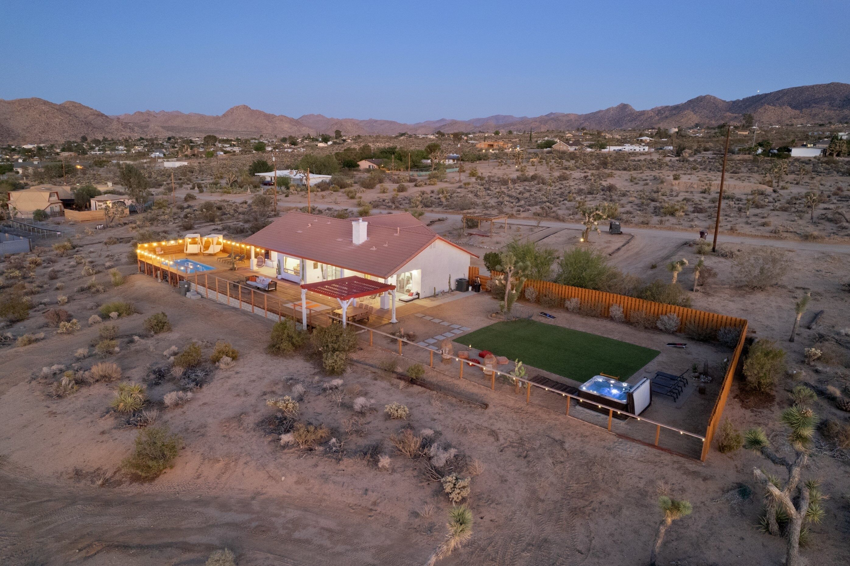 A house with a red roof, a fenced patio with outdoor furniture, and a swimming pool.