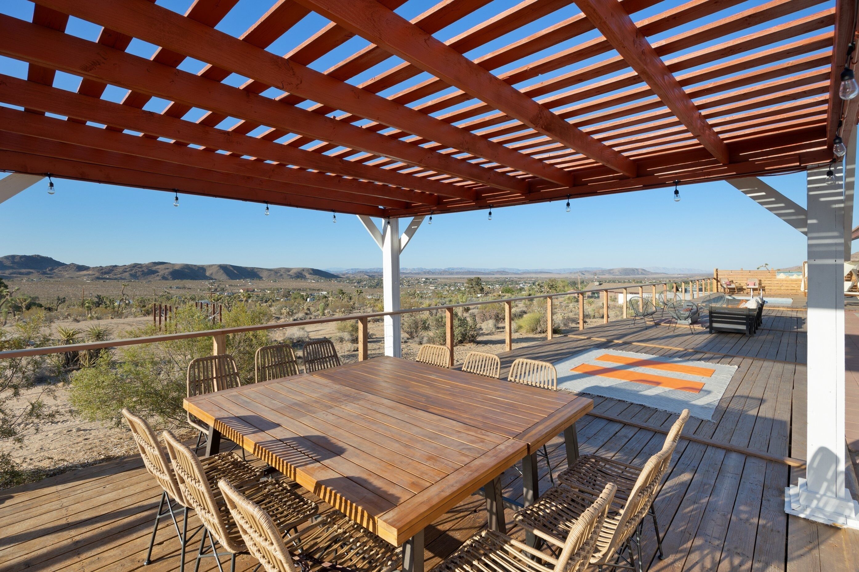 Una terraza de madera con una mesa y sillas, con vistas a un paisaje desértico.