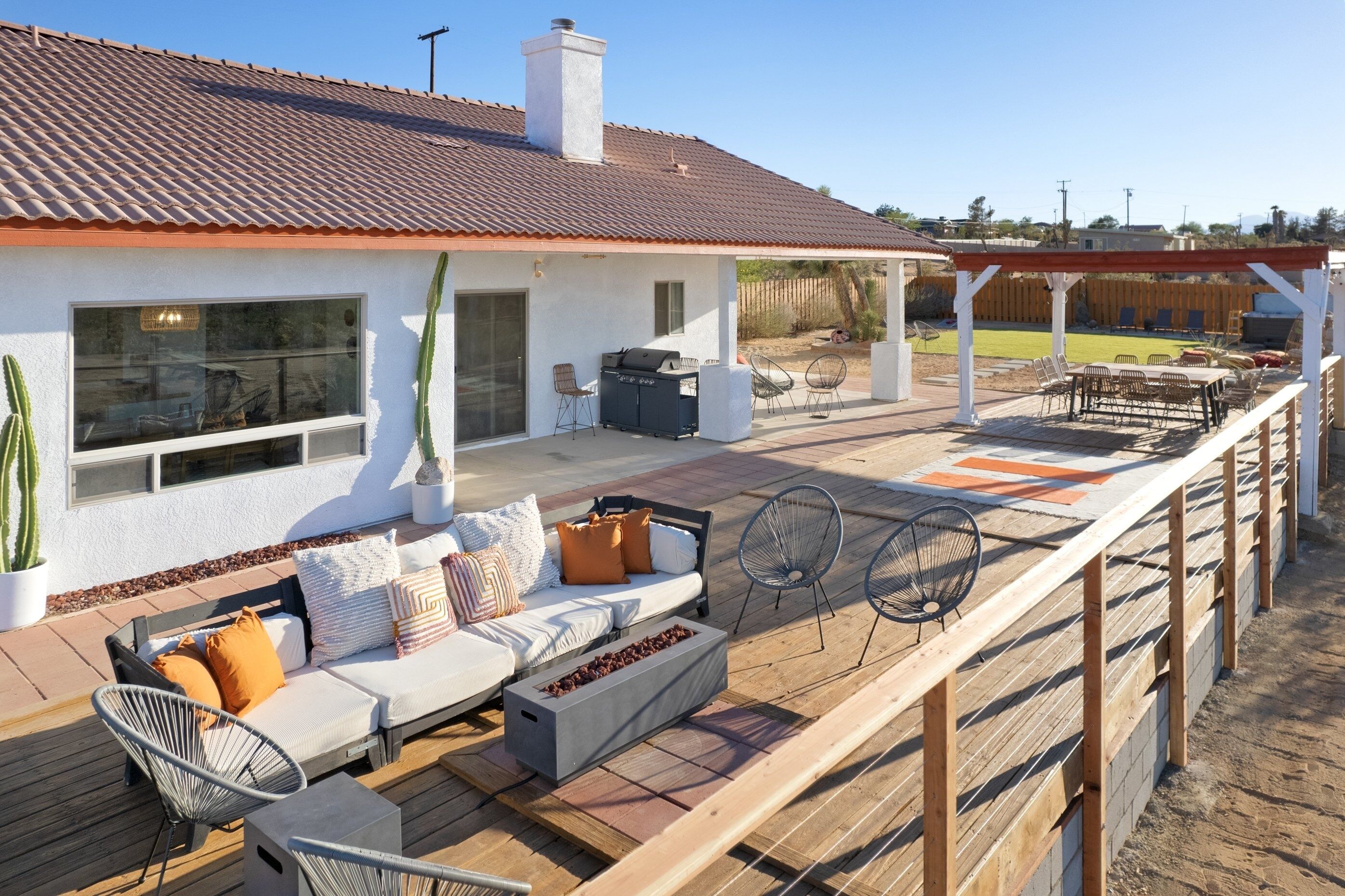 A covered outdoor patio with a sofa, chairs, and a grill.
