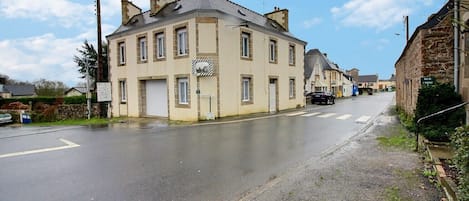 A two-story building with a garage door, a street in front, and a clear sky.