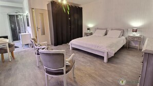 A bedroom with a large bed, two bedside tables, a chair, a desk, and a shower area. - Trémélois - TREMEL - Gîte (TREMEL)