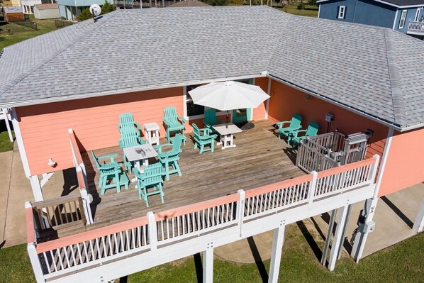 A covered deck with outdoor furniture and a white umbrella. - A Lil' Tipsea 4 Bedroom Home by RedAwning (Port Bolivar)