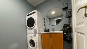 A laundry room with stacked washers and dryers, a sink, a mirror, and a door with a key lock. - Charming 2-bed Apartment in Stavanger (Stavanger)