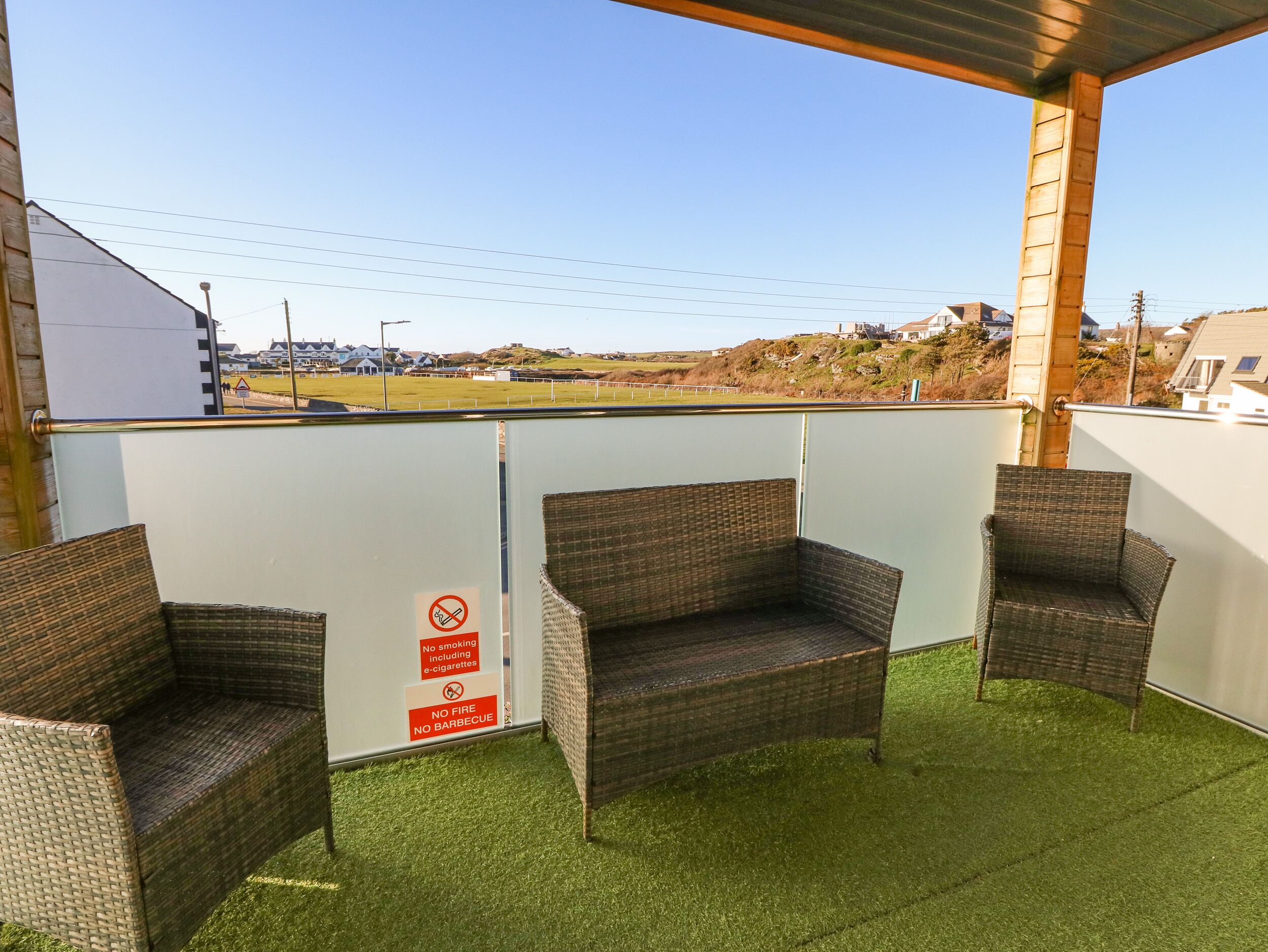 A covered outdoor seating area with wicker furniture and a sign prohibiting smoking and barbecue.