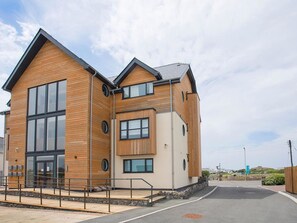 A modern building with a wooden facade, large windows, and a sloped roof. - 4 Y Bae (Holyhead)