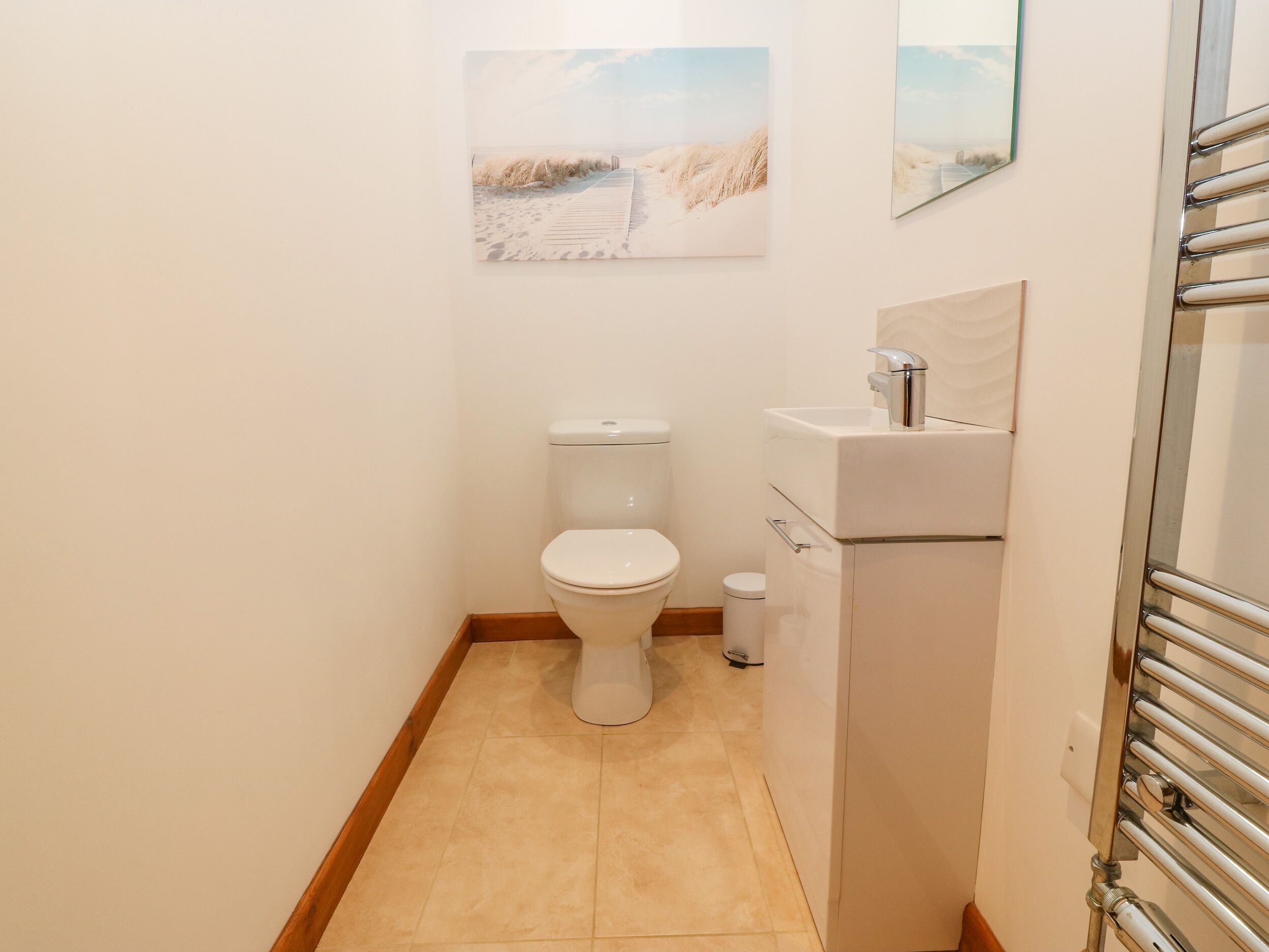A small bathroom with a toilet, sink, and a towel rack.