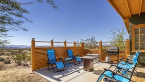 An outdoor patio with blue lounge chairs, a table, and a grill. - Martian Rose - Out Of This World Stargazing Cabin 2 Bedroom Home by RedAwning (Joshua Tree)