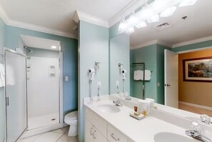 Bathroom features a large mirror, two sinks, and a shower area.