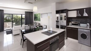 A modern kitchen with a central island, built-in appliances, and a dining area with a view to the outdoors. - The Capital 20 West (Johannesburg)