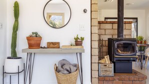 Una sala de estar con chimenea, un cactus y un espejo en la pared.