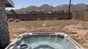 Un jacuzzi con pared de piedra y cerca de madera al fondo.