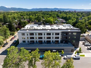 A multi-story building with a flat roof, several balconies, and a parking lot in front.