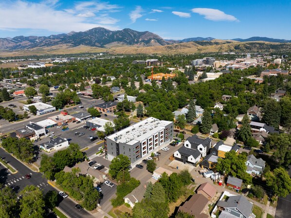 An aerial view of a town with a mix of residential and commercial buildings, surrounded by mountains.