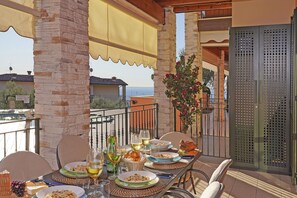 A balcony with a table set for a meal, featuring plates, glasses, and a bottle. - Le Terrazze PT 31 by Wonderful Italy (Toscolano Maderno)