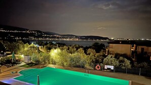 A swimming pool with a view of a cityscape at night. - Le Terrazze PT 31 by Wonderful Italy (Toscolano Maderno)
